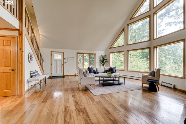 living room featuring a baseboard radiator, light wood-type flooring, and high vaulted ceiling