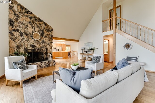 living room with a fireplace, light hardwood / wood-style flooring, and high vaulted ceiling