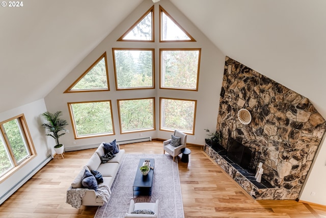 living room with a baseboard heating unit, light wood-type flooring, a premium fireplace, and a healthy amount of sunlight