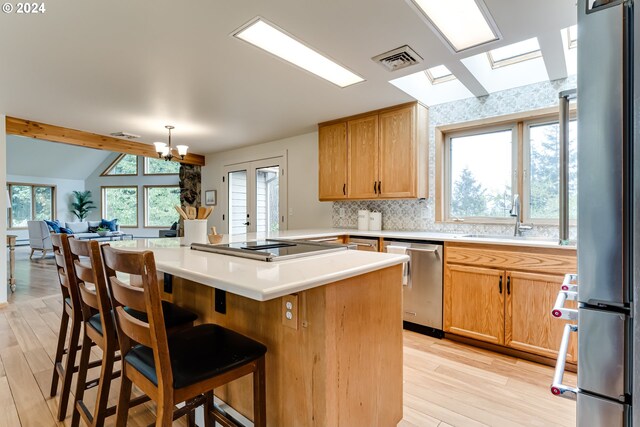 kitchen featuring lofted ceiling with beams, a breakfast bar, light hardwood / wood-style floors, tasteful backsplash, and appliances with stainless steel finishes