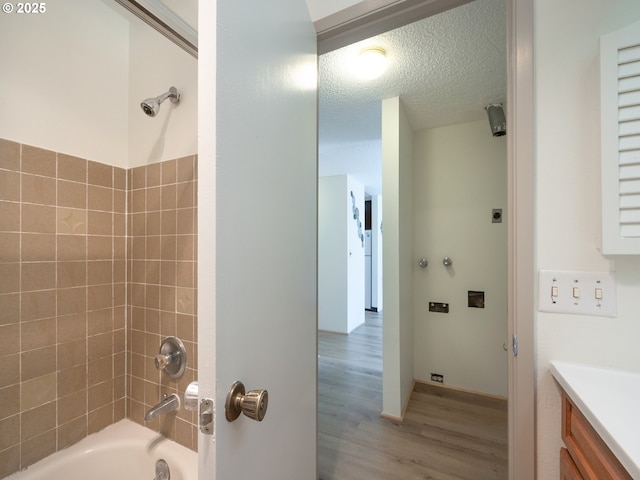 full bath with wood finished floors,  shower combination, a textured ceiling, and vanity