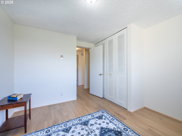 unfurnished bedroom featuring light wood finished floors, a closet, and a textured ceiling