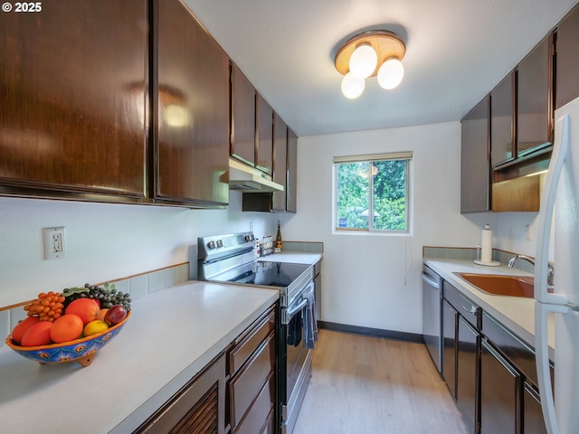 kitchen with stainless steel appliances, under cabinet range hood, light wood-type flooring, and light countertops