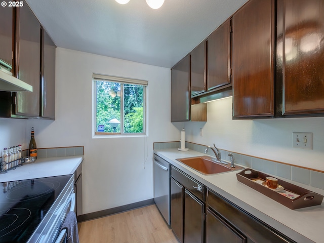 kitchen featuring a sink, dishwasher, light wood-style flooring, light countertops, and baseboards
