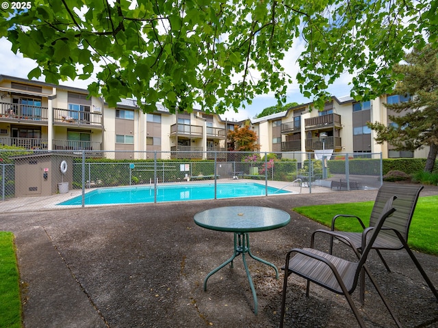 community pool featuring fence, a residential view, and a patio