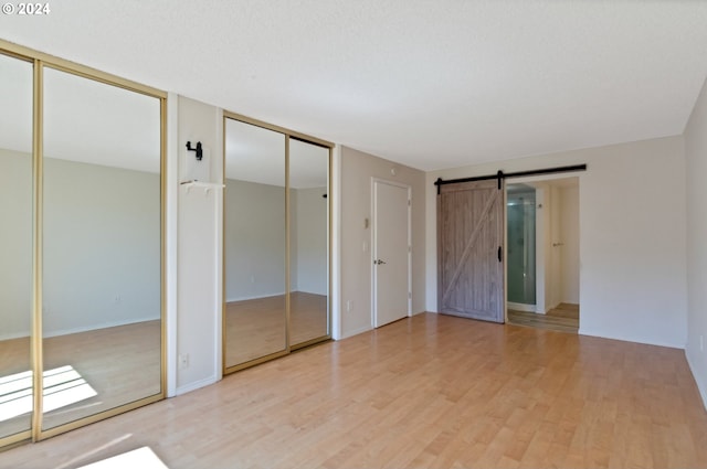 unfurnished room with a baseboard heating unit, a textured ceiling, and light wood-type flooring