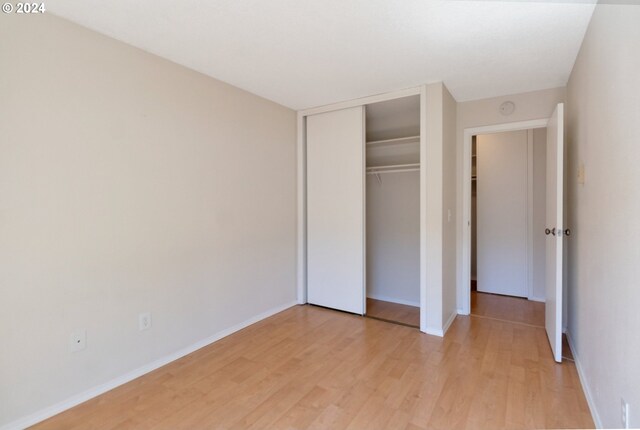 unfurnished bedroom featuring light wood-type flooring and a closet