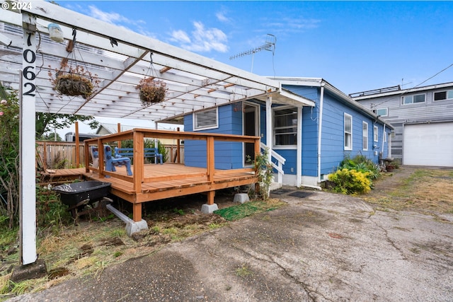 back of property featuring a garage, a pergola, and a wooden deck