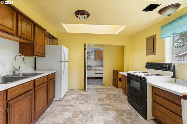 kitchen featuring a skylight, a tray ceiling, sink, light tile patterned flooring, and white appliances