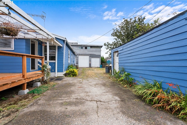 view of property exterior featuring a garage, aphalt driveway, and a wooden deck