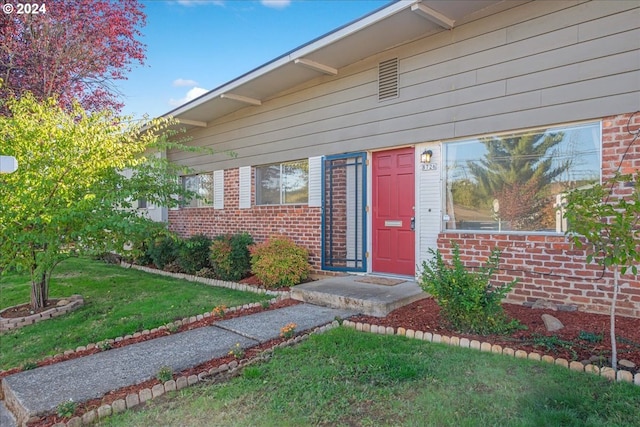 property entrance featuring a lawn