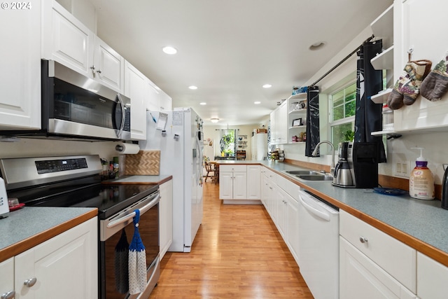 kitchen featuring stainless steel appliances, white cabinets, a sink, and open shelves