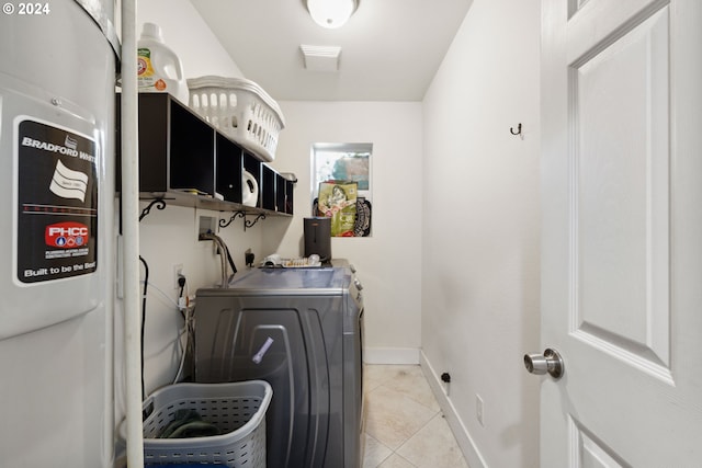 clothes washing area featuring laundry area, baseboards, washing machine and clothes dryer, and light tile patterned flooring