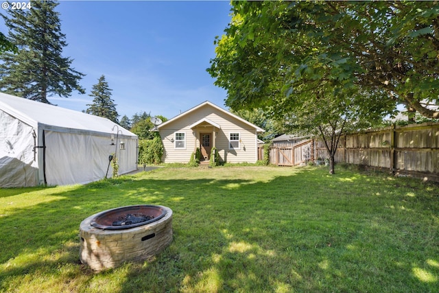 view of yard featuring entry steps, an outdoor fire pit, fence, and an outbuilding