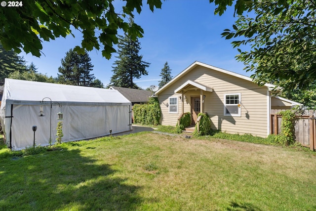 back of house featuring a lawn and fence