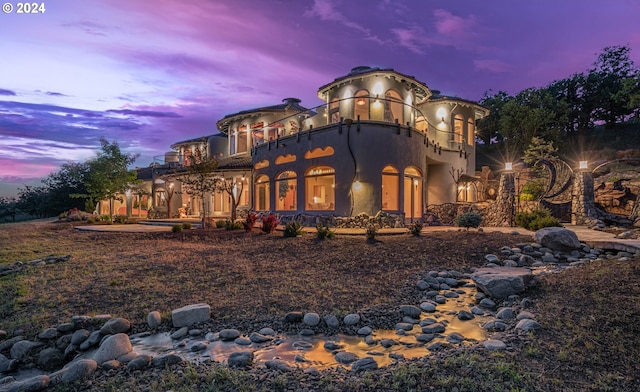 back house at dusk featuring a balcony