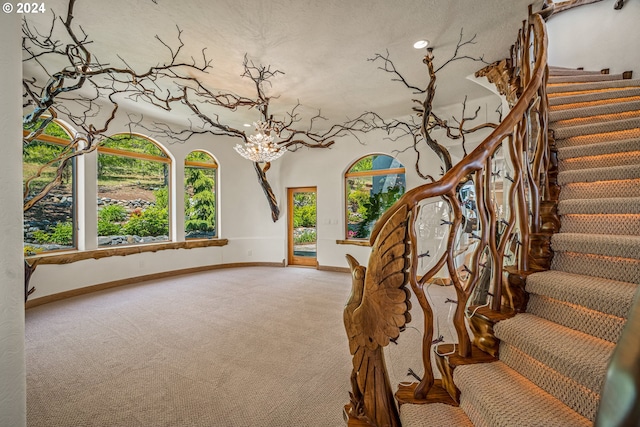 staircase with carpet floors and a chandelier