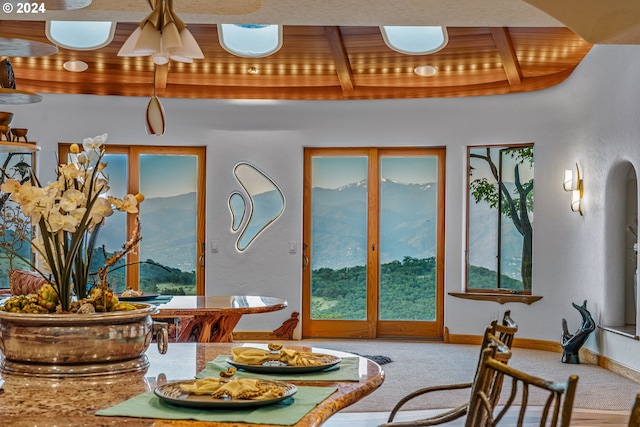 carpeted dining space featuring beamed ceiling and wooden ceiling