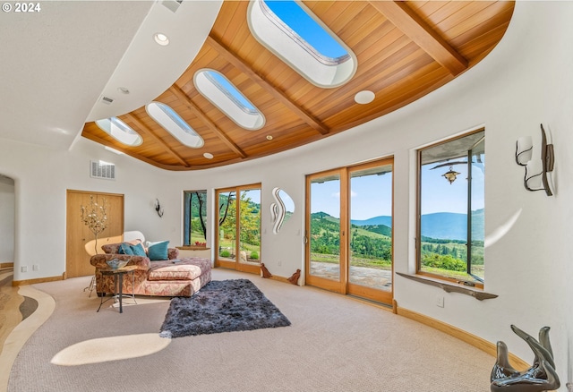 carpeted living room featuring high vaulted ceiling, a skylight, wood ceiling, a mountain view, and beam ceiling