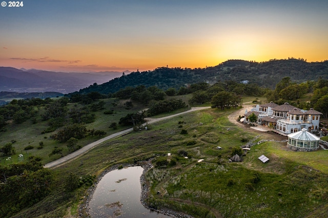 aerial view at dusk featuring a water and mountain view