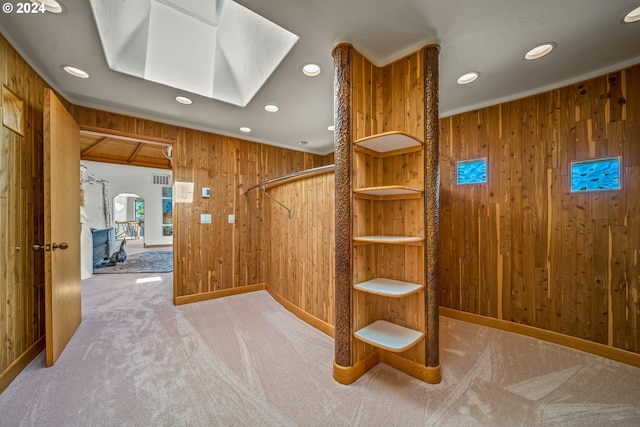 stairway with a skylight, wooden walls, and carpet flooring