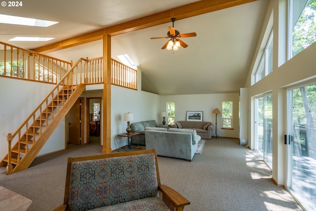 carpeted living room featuring beamed ceiling, ceiling fan, a skylight, and high vaulted ceiling