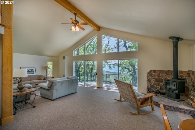 carpeted living room with ceiling fan, high vaulted ceiling, beamed ceiling, and a wood stove