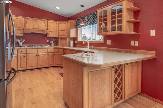 kitchen with kitchen peninsula, stainless steel fridge, premium range hood, sink, and pendant lighting