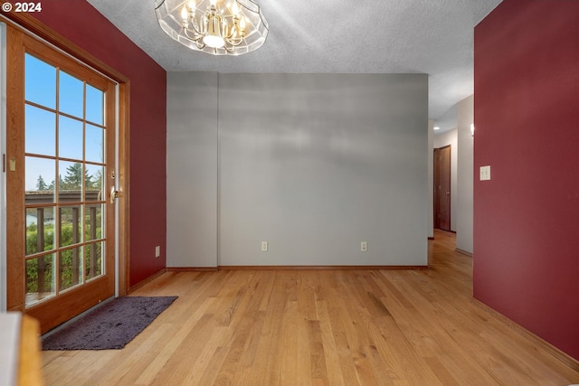 interior space with a chandelier, a healthy amount of sunlight, a textured ceiling, and light hardwood / wood-style flooring