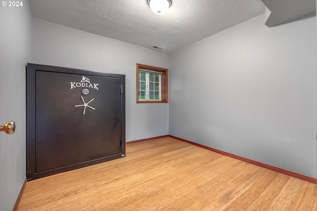 empty room featuring a textured ceiling and light hardwood / wood-style flooring