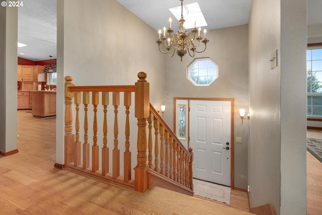 entrance foyer featuring light wood-type flooring, a skylight, an inviting chandelier, and a wealth of natural light