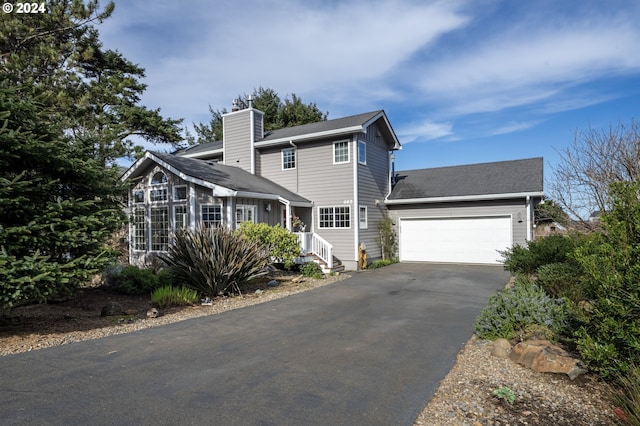 view of front of property featuring aphalt driveway, a chimney, and an attached garage