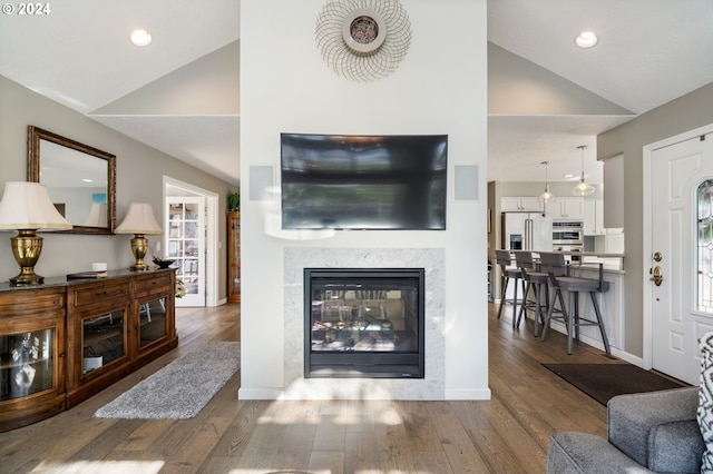 living room featuring lofted ceiling, wood finished floors, a multi sided fireplace, and baseboards