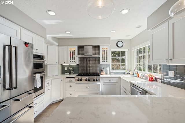 kitchen featuring light stone countertops, a sink, appliances with stainless steel finishes, white cabinetry, and backsplash