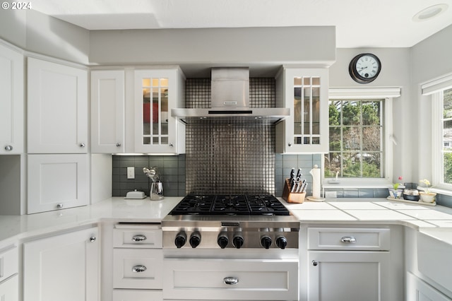 kitchen featuring decorative backsplash, wall chimney exhaust hood, white cabinets, and stainless steel gas cooktop