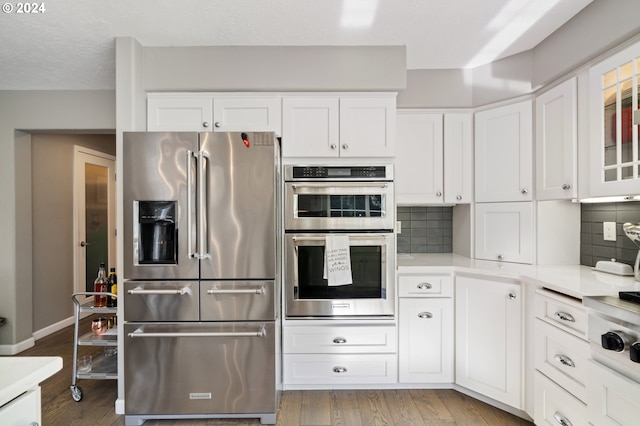 kitchen featuring backsplash, light wood-type flooring, light countertops, stainless steel appliances, and white cabinetry