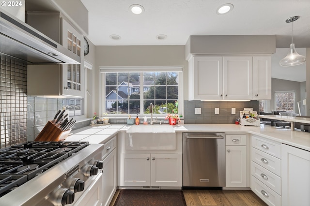 kitchen with wall chimney range hood, white cabinets, appliances with stainless steel finishes, and a sink