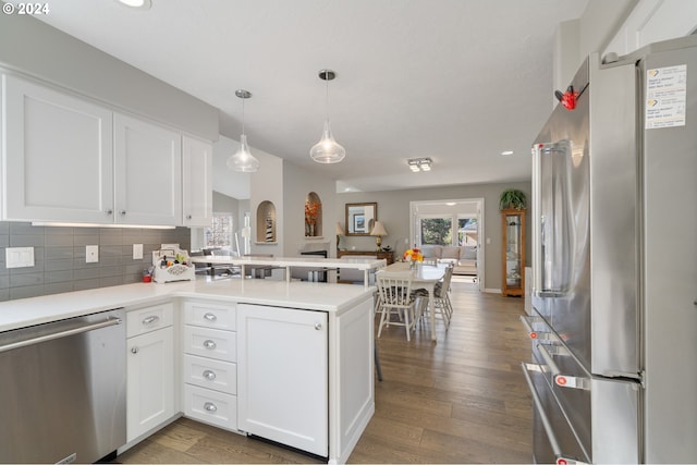 kitchen with stainless steel appliances, wood finished floors, a peninsula, and white cabinets