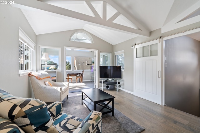 living area featuring a barn door, plenty of natural light, wood finished floors, and lofted ceiling