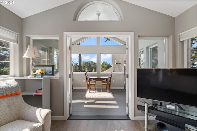 doorway to outside featuring baseboards, lofted ceiling, and wood finished floors