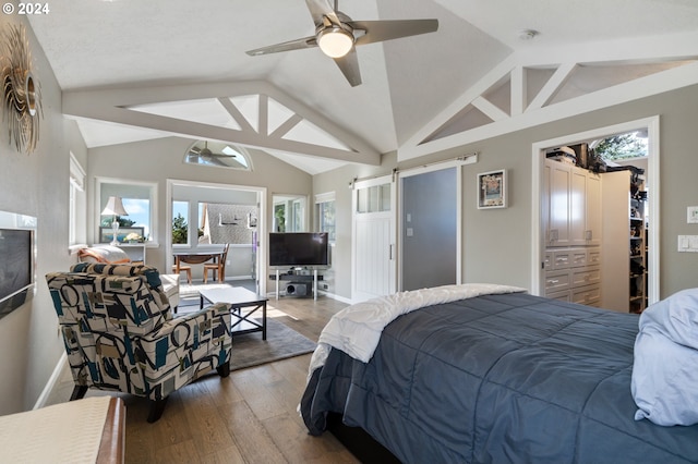 bedroom featuring multiple windows, lofted ceiling, a barn door, and wood finished floors