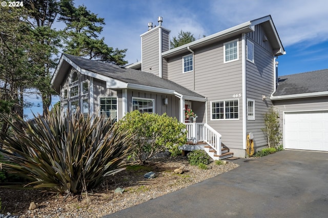 view of front of home featuring a garage, driveway, board and batten siding, and a chimney