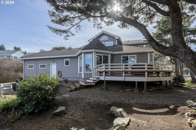 rear view of house with a wooden deck and roof with shingles