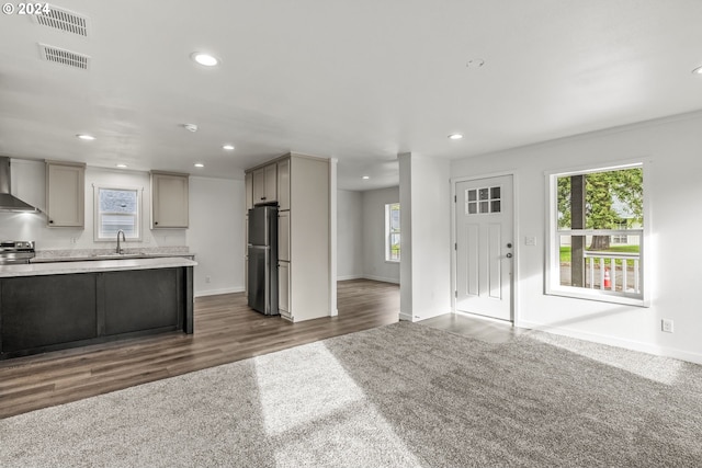 kitchen with wall chimney exhaust hood, dark colored carpet, and gray cabinets