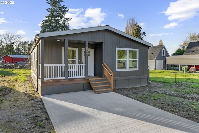 manufactured / mobile home featuring covered porch, a carport, and a front yard