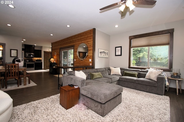 living room featuring wooden walls, ceiling fan, and dark hardwood / wood-style flooring