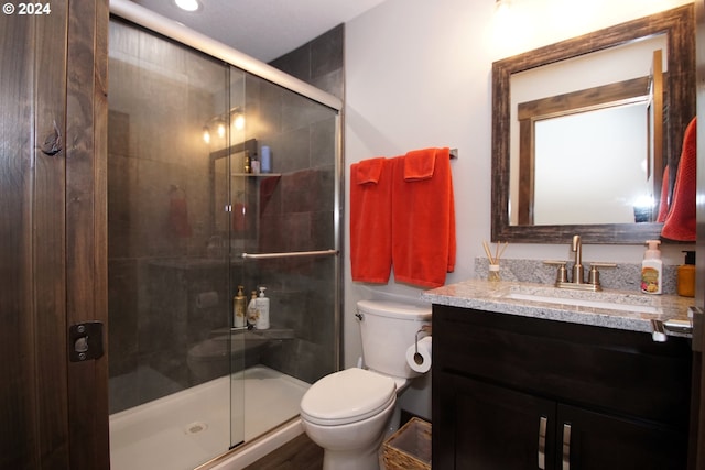 bathroom with toilet, a shower with shower door, and vanity