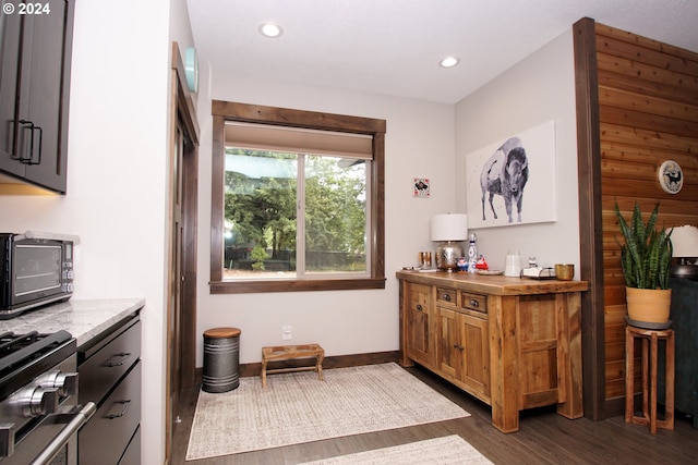 bar with dark hardwood / wood-style flooring, rustic walls, and stainless steel range with gas cooktop