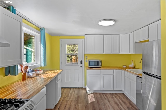 kitchen with white cabinets, sink, wooden counters, appliances with stainless steel finishes, and light wood-type flooring