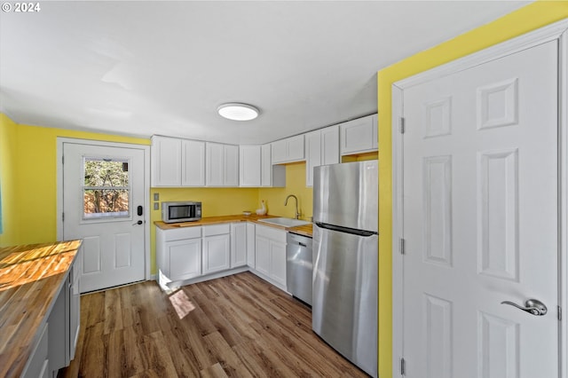 kitchen with white cabinets, sink, wooden counters, stainless steel appliances, and light wood-type flooring